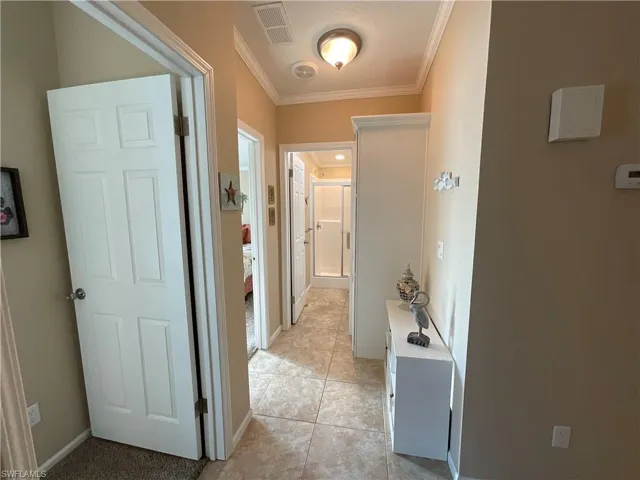 Hall featuring light tile patterned floors and crown molding