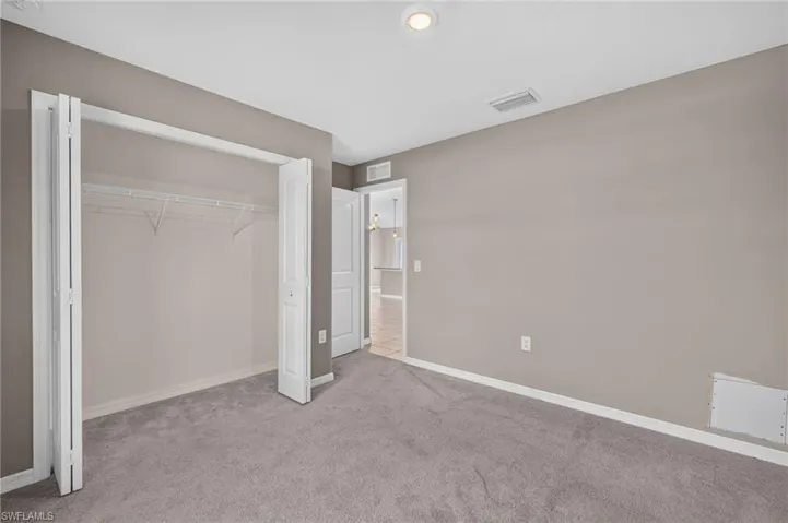 Wall-to-wall carpeting, neutral wall color, recessed lighting, and bifold closet doors