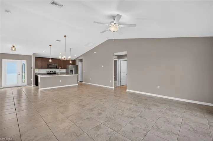 Vaulted ceiling, tiled flooring, wood cabinetry, stainless steel appliances, and a central island