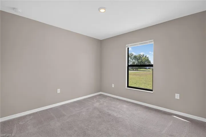 Neutral tone wall paint, recessed ceiling lighting, carpeted flooring, and a window with blinds