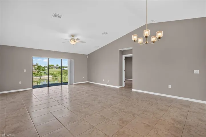 Tiled flooring throughout, vaulted ceiling, and sliding glass doors with a water feature backdrop