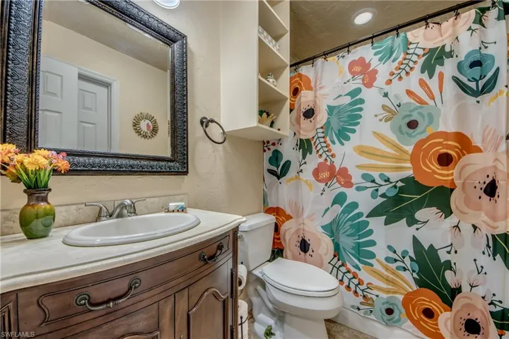 Full bathroom with a shower with shower curtain, vanity, and a textured wall