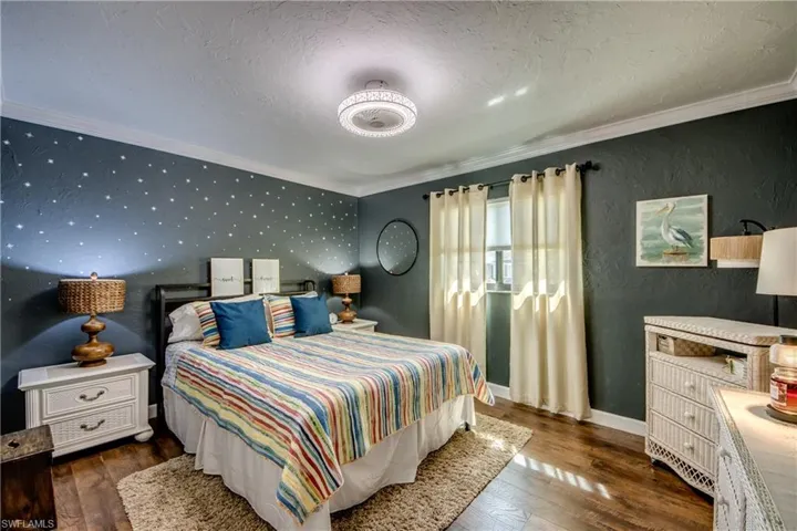 Bedroom with crown molding, dark wood-style floors, a textured ceiling, and a textured wall