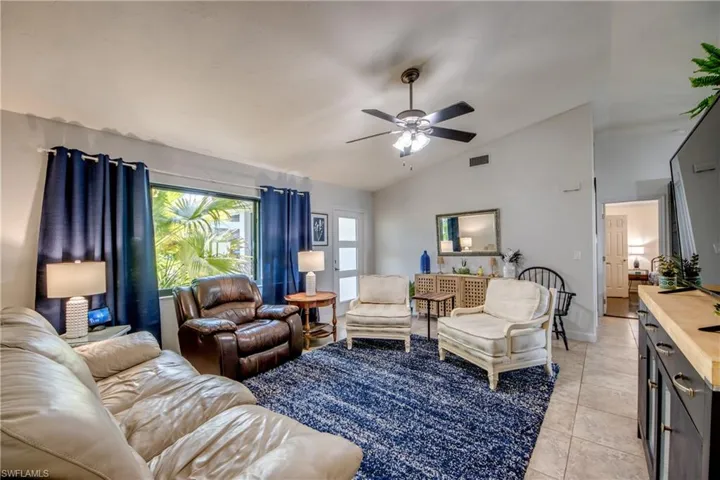 Living area featuring vaulted ceiling, a ceiling fan, and light tile patterned flooring