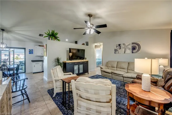 Living area with hanging lights, lofted ceiling, light tile patterned floors, and a ceiling fan