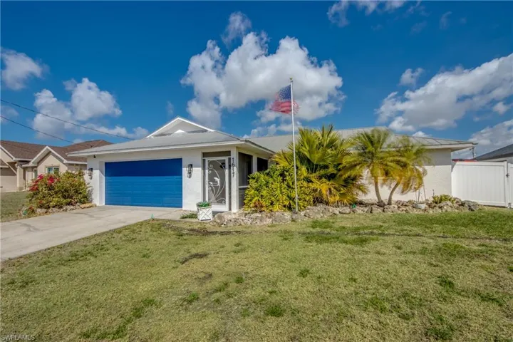 Single story home featuring driveway, a front lawn, an attached garage, and stucco siding