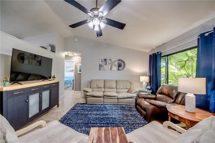 Living area featuring vaulted ceiling, a ceiling fan, and light tile patterned floors