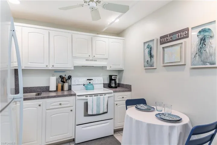Kitchen featuring ceiling fan, light tile patterned floors, white cabinets, and white appliances