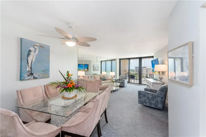 Carpeted dining area with ceiling fan and floor to ceiling windows