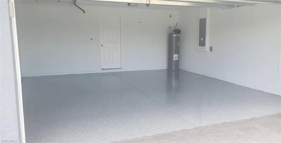 Garage featuring electric water heater, a garage door opener, and electric panel