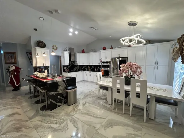 Dining room featuring light marble finish flooring and vaulted ceiling