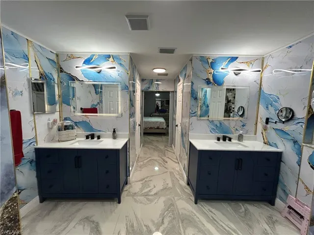 Full bathroom with ensuite bathroom, two vanities, and stone wall