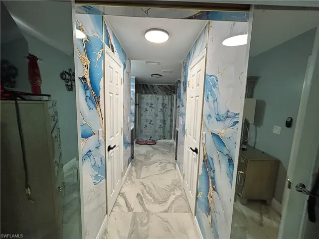 Full bath featuring light marble finish floors and a stall shower
