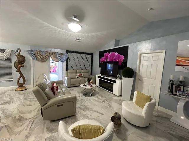 Living room featuring lofted ceiling and light marble finish floors