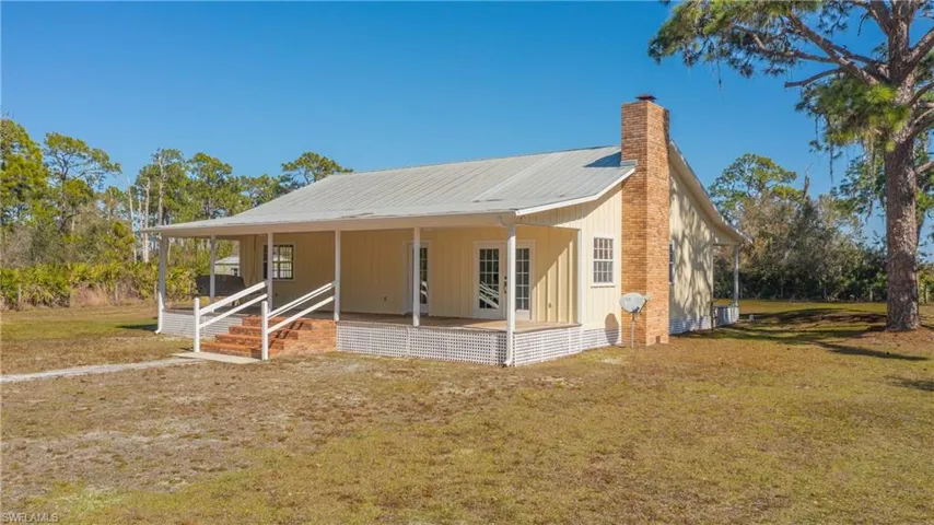 View of front of property with a large porch, a chimney, a front lawn, and a metal roof