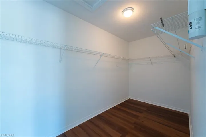 Walk in closet with dark wood finished floors