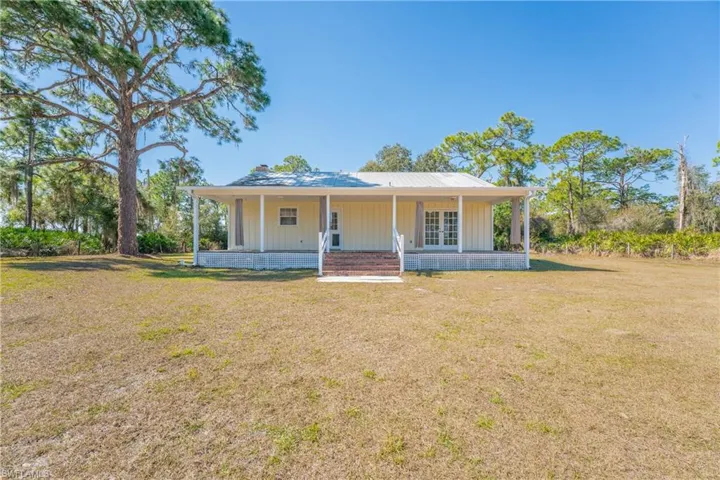 Farmhouse-style home with a front lawn, covered porch, a chimney, and board and batten siding