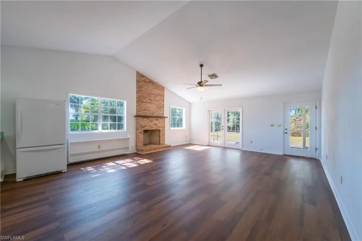 Unfurnished living room featuring ceiling fan, a fireplace, dark wood finished floors, french doors, and baseboard heating