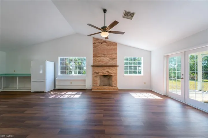 Unfurnished living room with a ceiling fan, french doors, plenty of natural light, and dark wood-type flooring