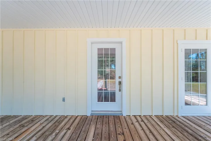 Entrance to property with board and batten siding and a deck