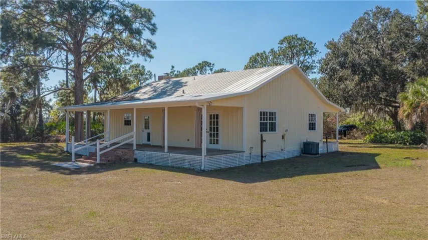 View of front facade featuring a front lawn, a porch, and a metal roof