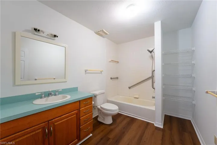 Full bath featuring vanity, dark wood finished floors, and shower / washtub combination