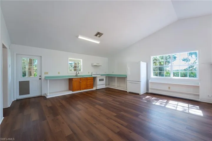 Kitchen with white appliances, light countertops, healthy amount of natural light, dark wood-style floors, and lofted ceiling