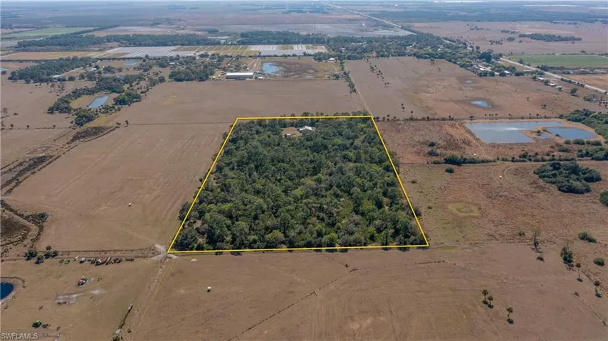 Aerial view of sparsely populated area with large plots for crops and property parcel outlined