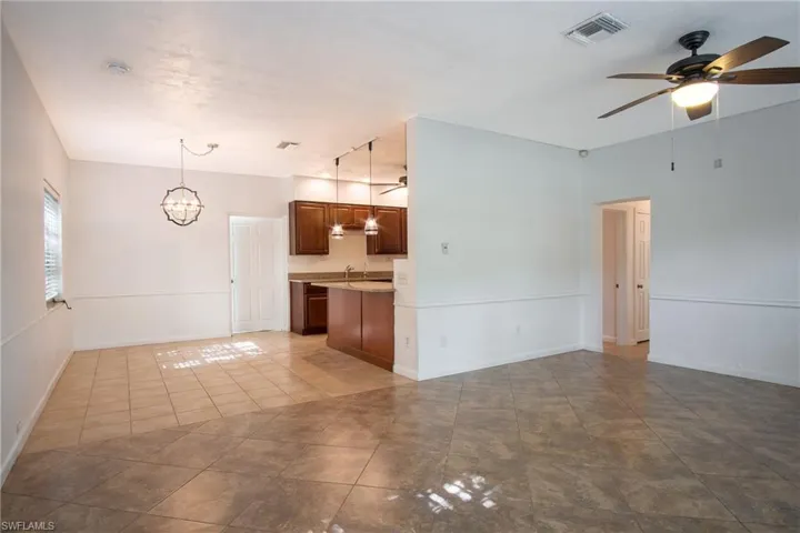 Kitchen featuring ceiling fan with notable chandelier, light tile patterned floors, hanging light fixtures, and sink