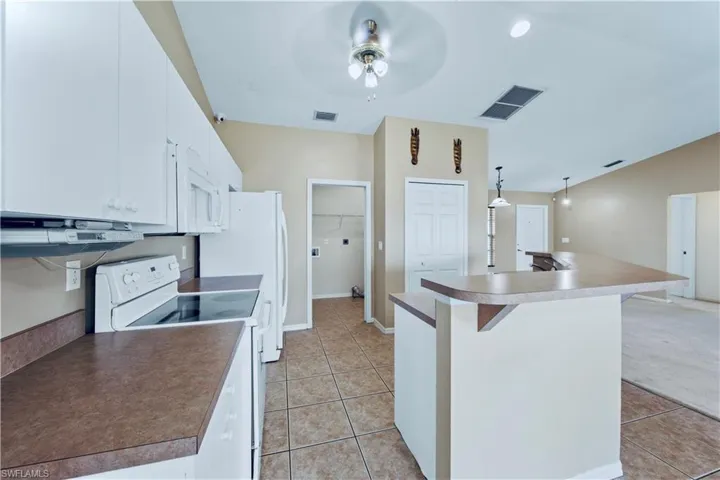 Kitchen featuring visible vents, a ceiling fan, white appliances, and light tile patterned flooring