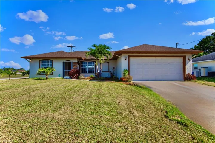 Ranch-style home featuring concrete driveway, a front lawn, an attached garage, and stucco siding