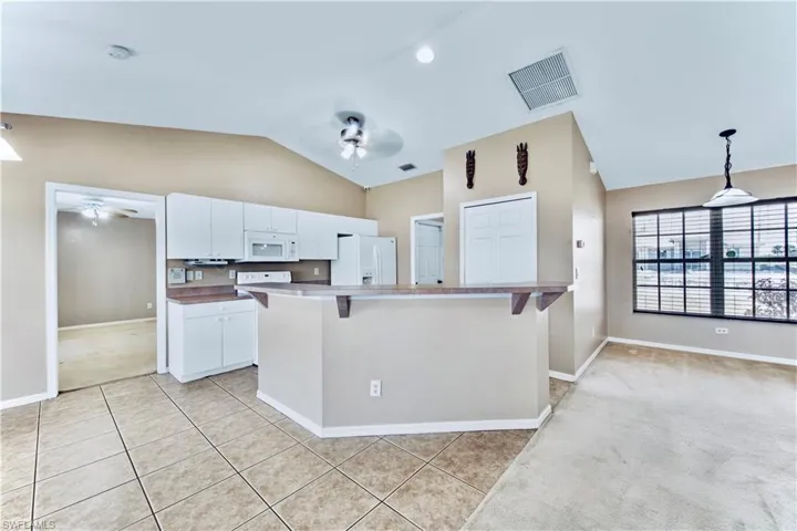 Kitchen featuring white appliances, visible vents, a ceiling fan, and lofted ceiling