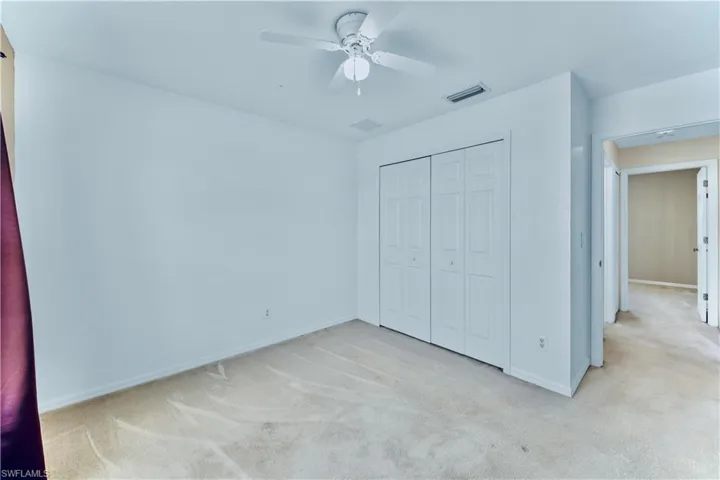 Unfurnished bedroom featuring a closet, baseboards, a ceiling fan, visible vents, and carpet