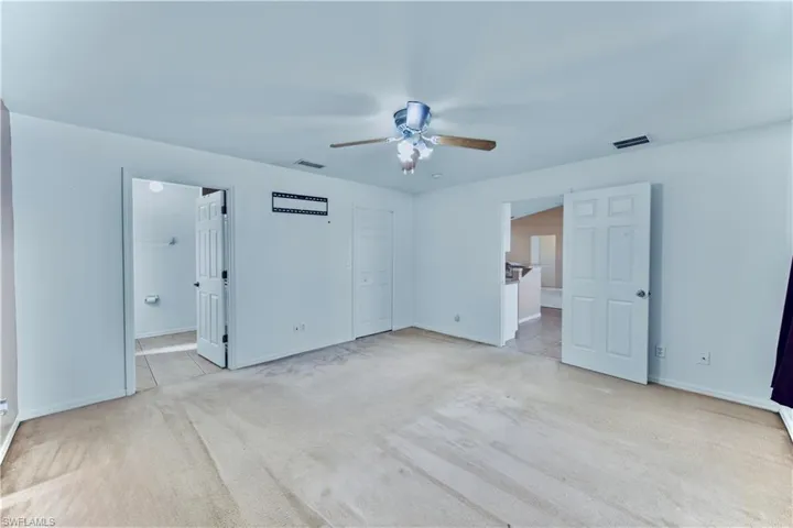 Unfurnished bedroom featuring light carpet, ceiling fan, baseboards, and visible vents