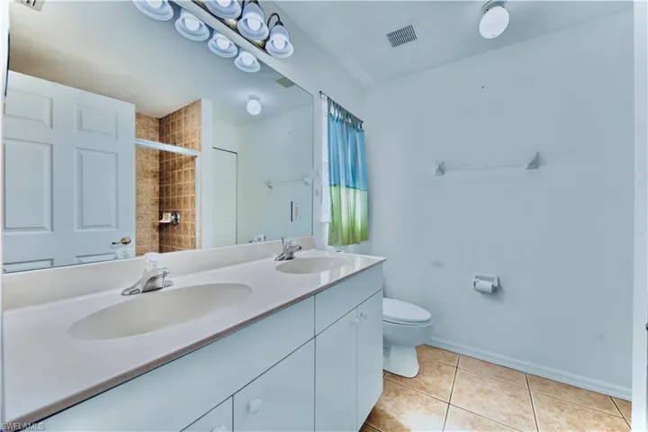Full bath featuring toilet, tile patterned floors, a sink, and visible vents