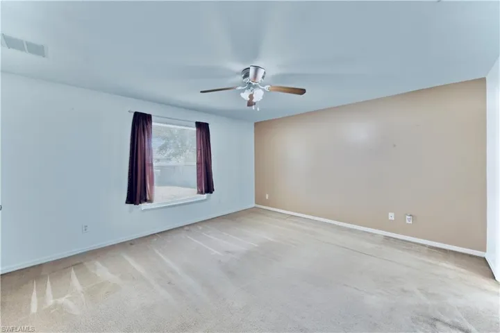 Empty room with light colored carpet, baseboards, a ceiling fan, and visible vents