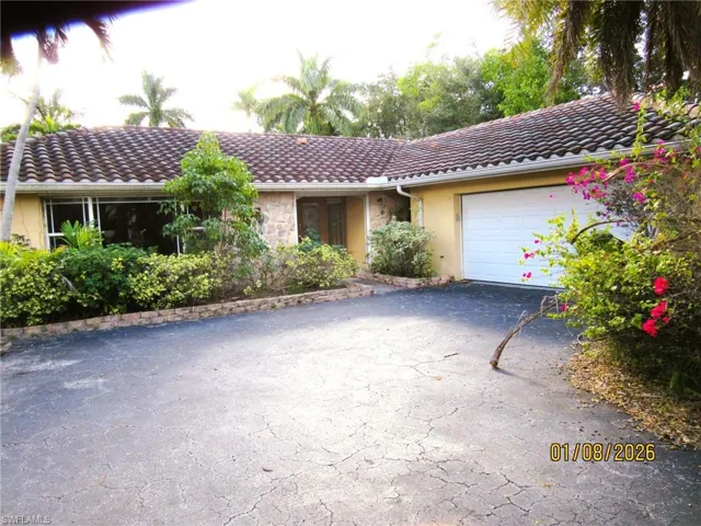 View of front of house featuring a tile roof, driveway, stucco siding, and an attached garage
