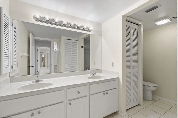 Full bath featuring a closet, double vanity, and light tile patterned floors