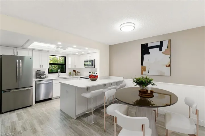 Kitchen with stainless steel appliances, a peninsula, white cabinetry, a breakfast bar area, and a ceiling fan