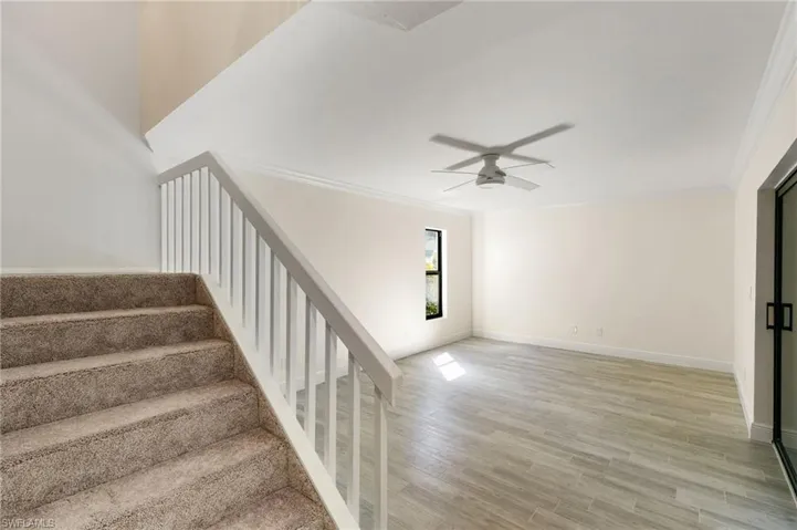 Stairs with crown molding, wood finished floors, and ceiling fan
