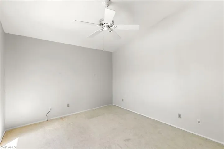 Unfurnished room featuring ceiling fan, carpet, and lofted ceiling