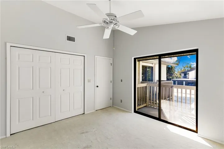 Unfurnished bedroom with carpet, access to exterior, lofted ceiling, a closet, and a ceiling fan