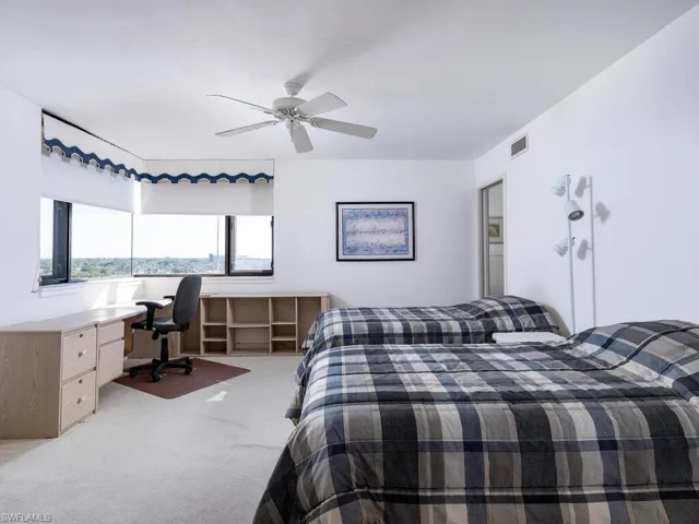 Carpeted bedroom with ceiling fan and built in desk