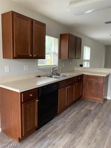 Kitchen with light countertops, black dishwasher, a peninsula, and light wood finished floors