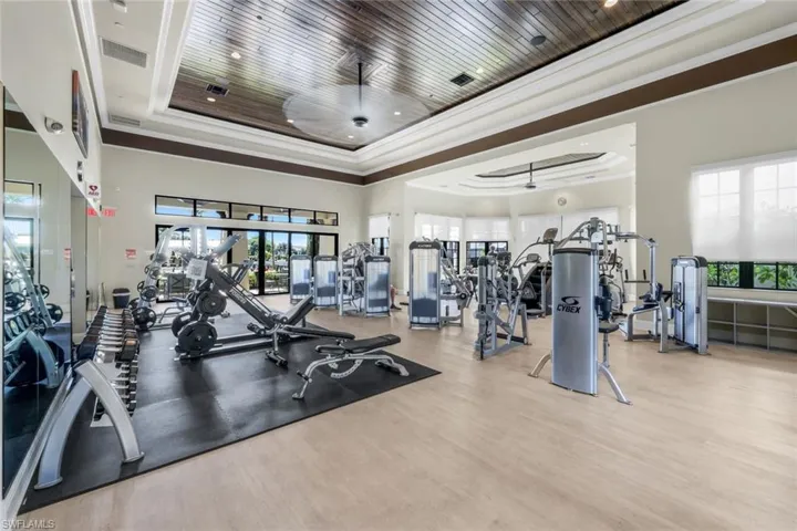 Exercise room featuring a raised ceiling, crown molding, healthy amount of natural light, wood finished floors, and recessed lighting