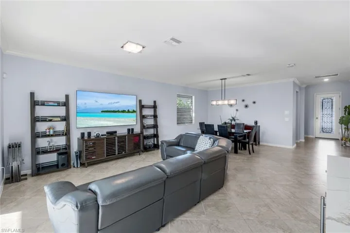 Living area featuring crown molding and light tile patterned flooring