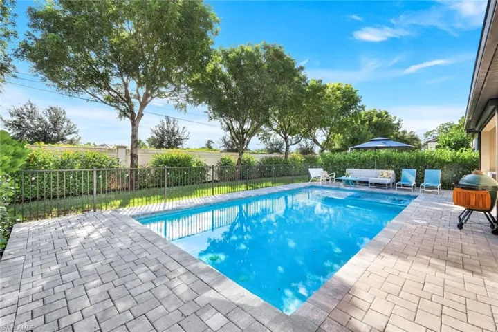 View of swimming pool featuring a patio area, a fenced backyard, and a grill