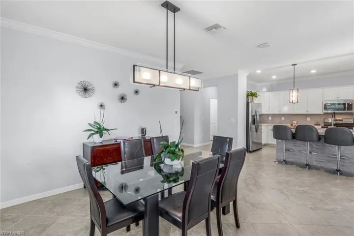 Dining area with ornamental molding, recessed lighting, and light tile patterned floors