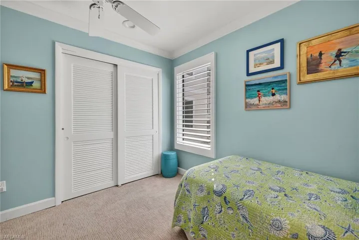 Bedroom with carpet flooring, ornamental molding, a closet, and a ceiling fan