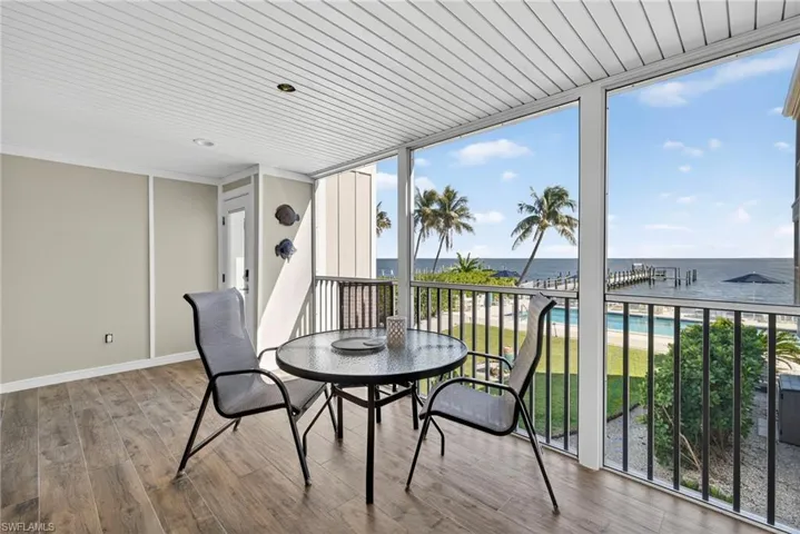 Sunroom / solarium featuring floor to ceiling windows, wood finished floors, and a water view